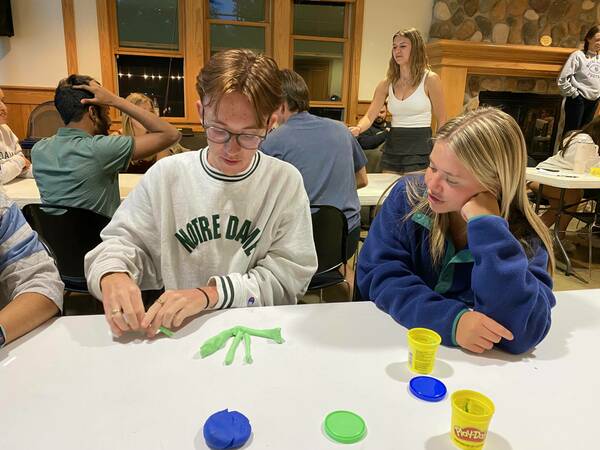 A Close Up Of Two Sheedy Family Students Involved In A Game Night Activity At A Table Indoors