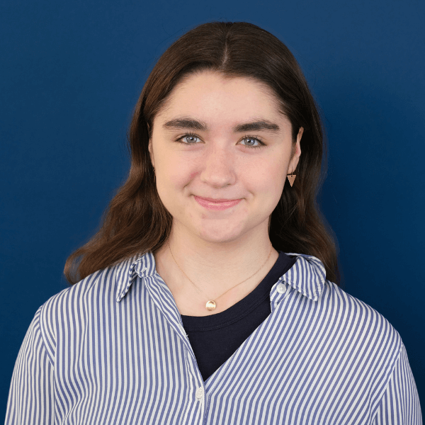 Headshot of Sheedy student Jayne Kelly, with a blue background behind her