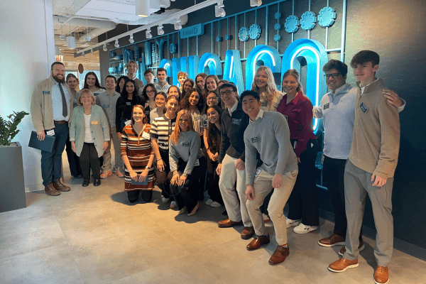 A group of Notre Dame students and faculty pose for a photo in front of a teal LinkedIn Chicago sign.