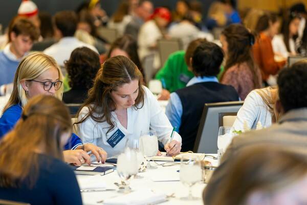 College students gather at tables for a dinner and dialogue event